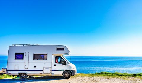 Vue de profil d'un camping car au bord de mer et par un grand ciel bleu