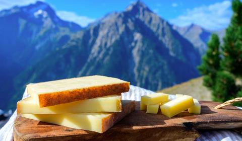 Une planche de fromage Comté AOP devant les montagnes du Jura en arrière-plan