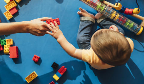 Un enfant et une assistante maternelle jouant sur un tapis d'éveil bleu
