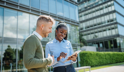 Deux collaborateur·ice·s travaillant avec le sourire devant des bureaux à l'architecture moderne 