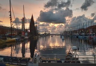Voiliers de la course Transat Jacques Vabre à quai dans la marina, au soleil couchant