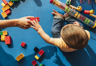 Un enfant et une assistante maternelle jouant sur un tapis d'éveil bleu