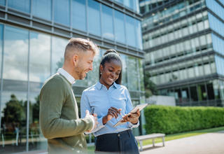 Deux collaborateur·ice·s travaillant avec le sourire devant des bureaux à l'architecture moderne 