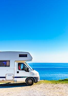 Vue de profil d'un camping car au bord de mer et par un grand ciel bleu