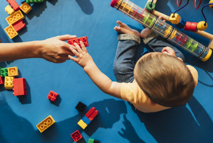 Un enfant et une assistante maternelle jouant sur un tapis d'éveil bleu