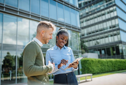 Deux collaborateur·ice·s travaillant avec le sourire devant des bureaux à l'architecture moderne 
