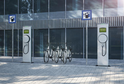 Best Place 2 Move : une borne de stationnement de vélos électriques devant une résidence moderne.